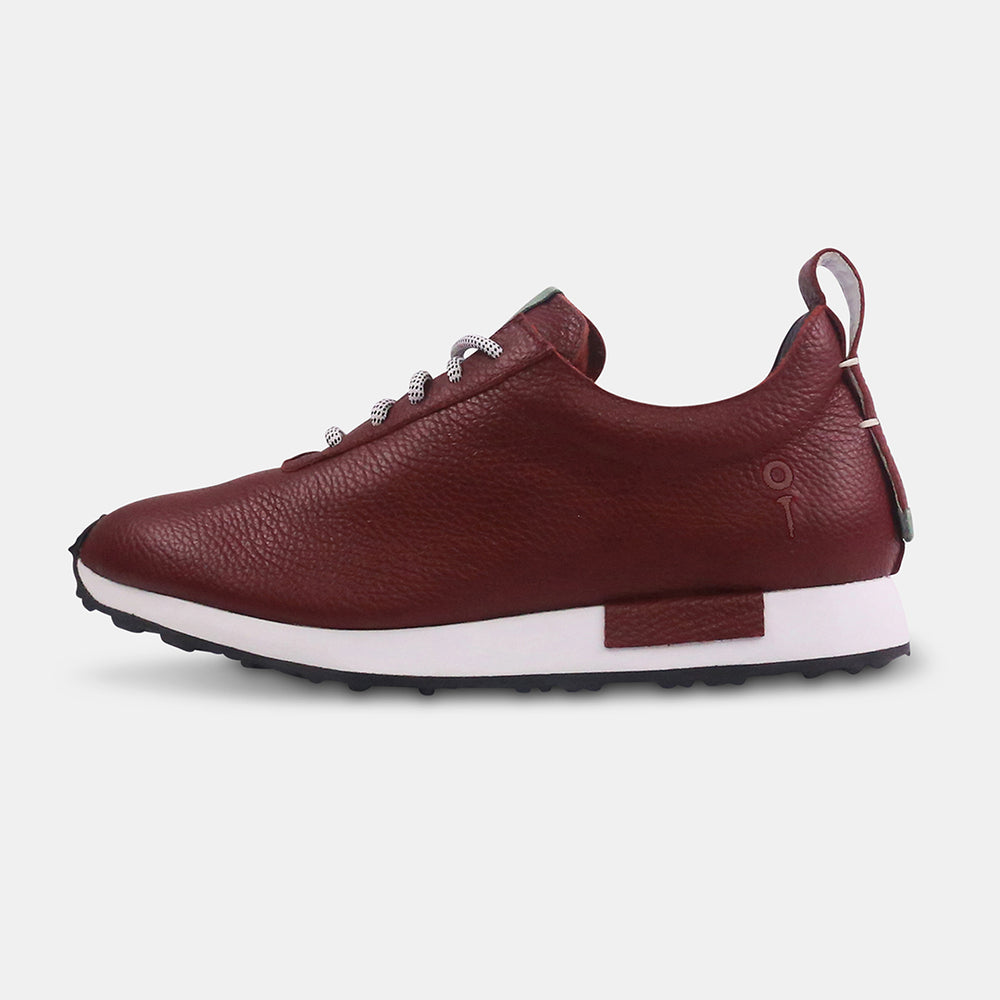 A pair of burgundy-colored leather golf sneakers with white soles and black laces with white flecks. The shoes have a small mint green accent on the tongue and a burgundy leather pull tab on the back.
