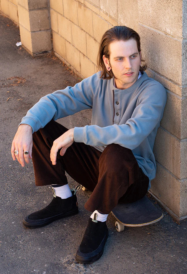 a man on a skateboard wearing slip on black shoes