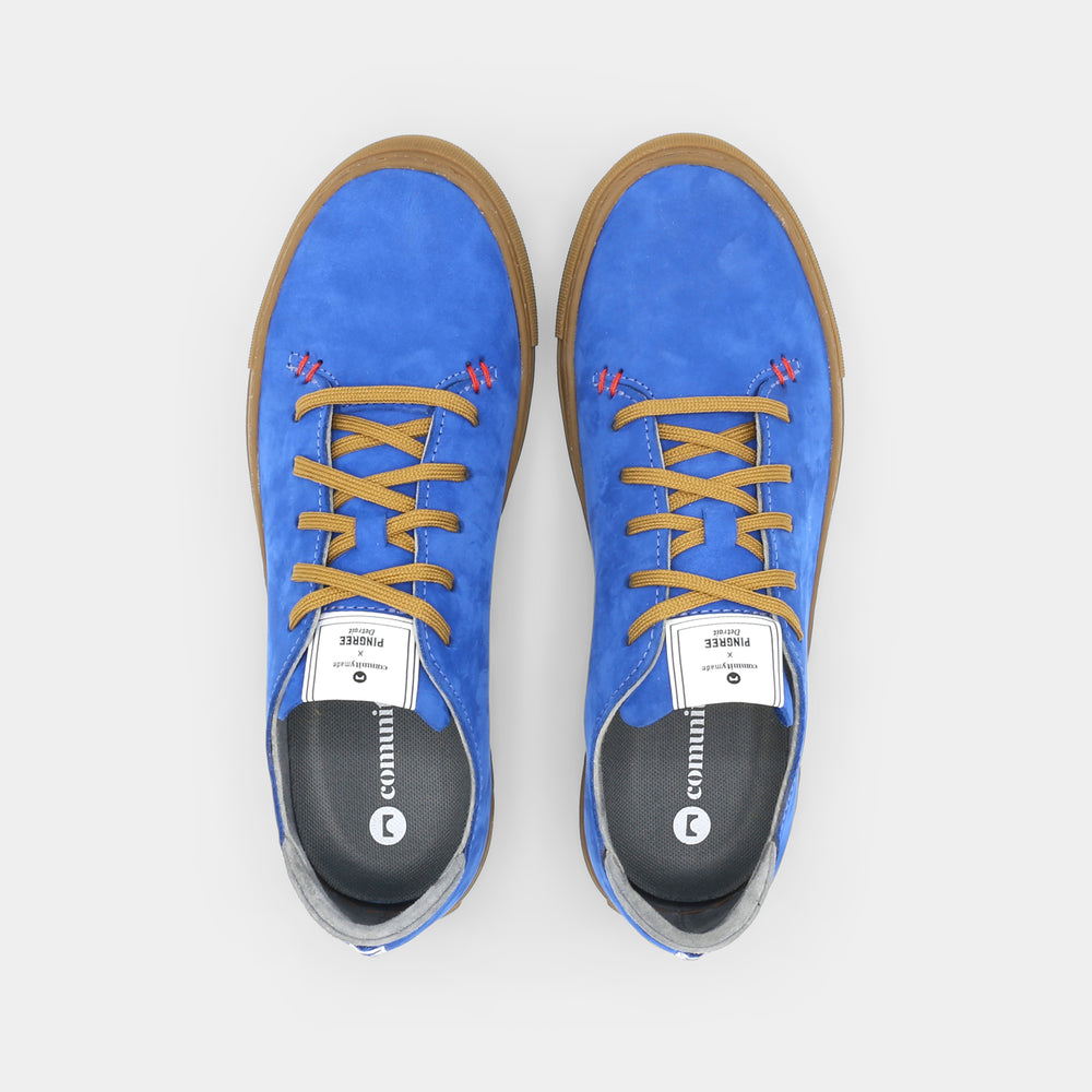 
                      
                        A blue low-top sneaker with a brown sole and laces, top view.
                      
                    