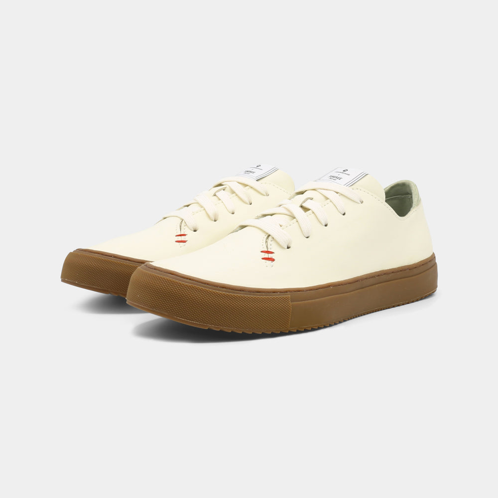 
                      
                        A latte colored low-top sneaker with a brown sole and white laces, quarter view.
                      
                    