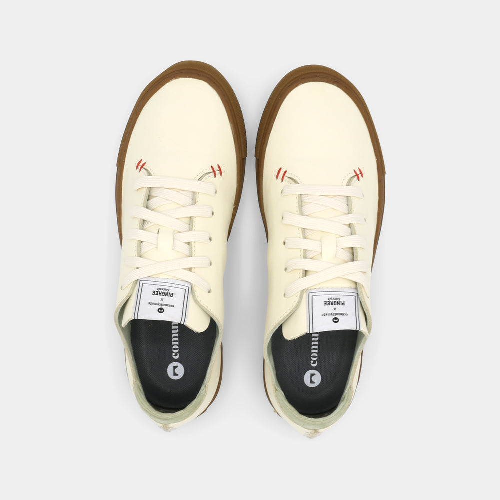 
                      
                        A latte colored low-top sneaker with a brown sole and white laces, top view.
                      
                    