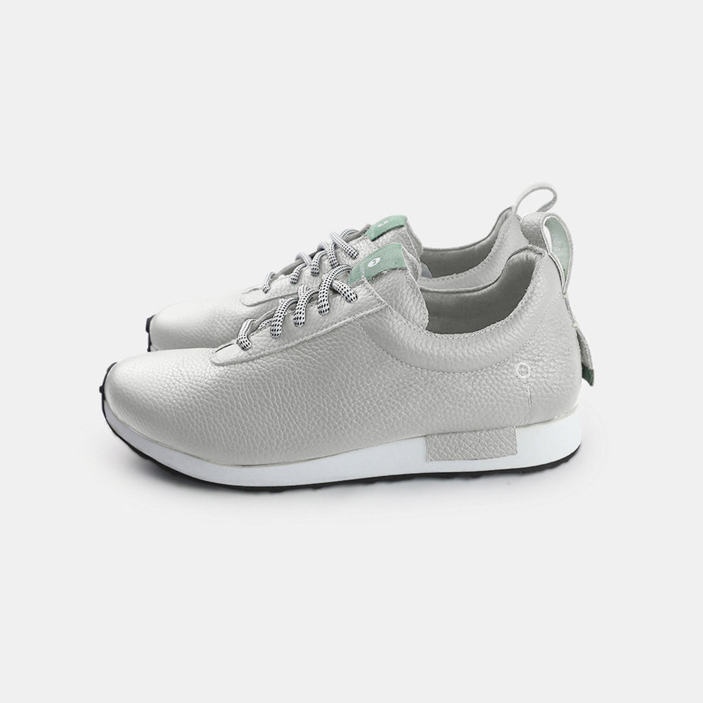 
                      
                        A pair of gray sneakers with a subtle grainy texture and white soles. A small mint green tag is at the base of the heel, just above the sole. A small white text logo is printed vertically on the back of each shoe.
                      
                    