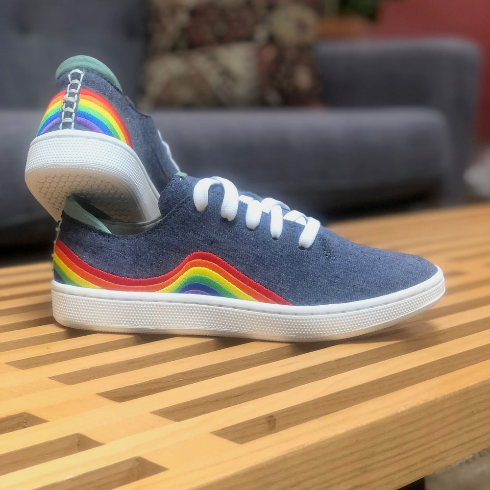 
                      
                        Picture of a pair of shoes that are made from denim that have a rainbow embroidery on the side that are sitting on a wood table
                      
                    