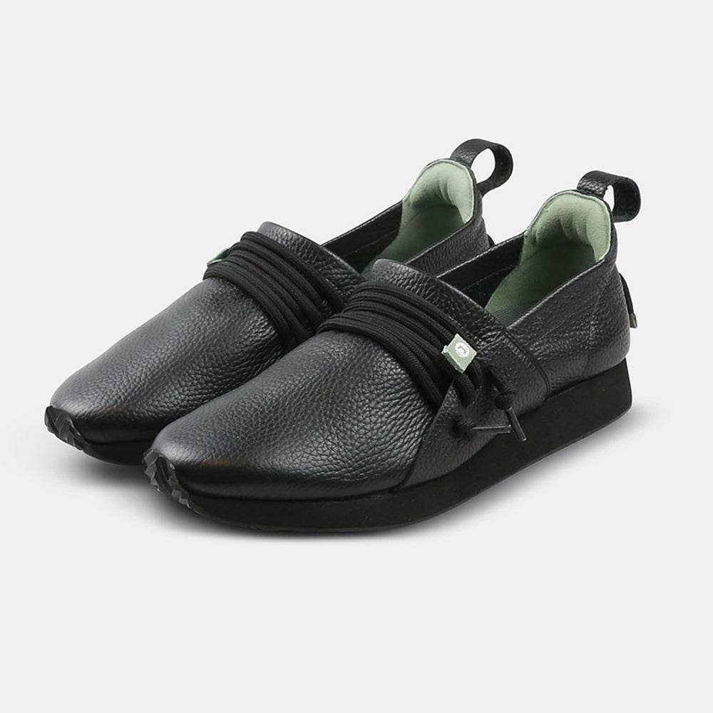 
                      
                        A three-quarter view of two Comunitymade "Mateo Stealth" shoes. The shoes are black, with a pebbled leather texture, black soles, and black laces cinched by a mint green lace lock. The inside of the shoe is lined with a light green color.
                      
                    