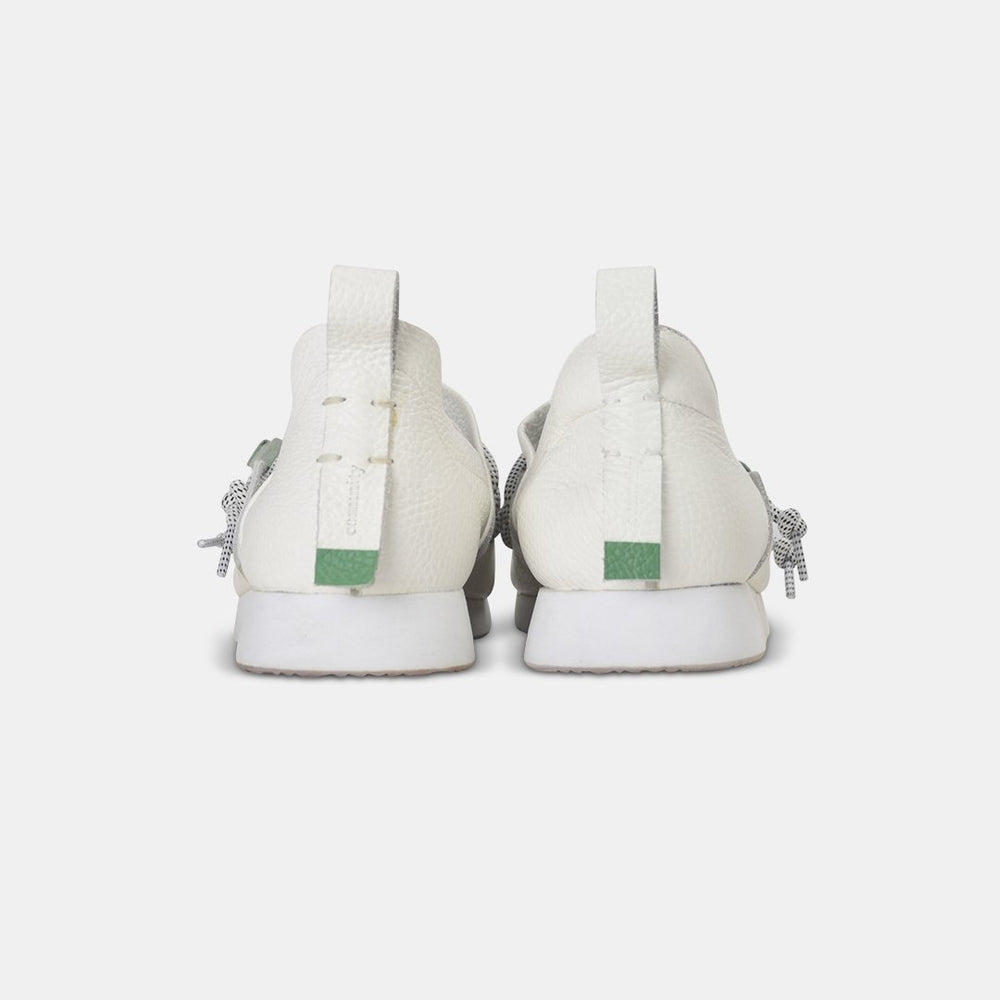 
                      
                        A rear view of two white Comunitymade shoes with white speckled leather. The shoes have thick white soles and a small, mint green rectangular patch on the back of each heel. The white pull tabs have a subtle "comunitymade" logo in vertical text.
                      
                    