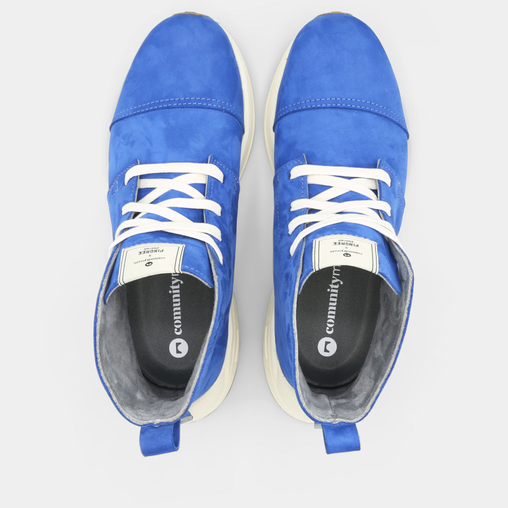 
                      
                        A blue high-top urban utility chukka boot with white laces and a chunky white sole top view.
                      
                    