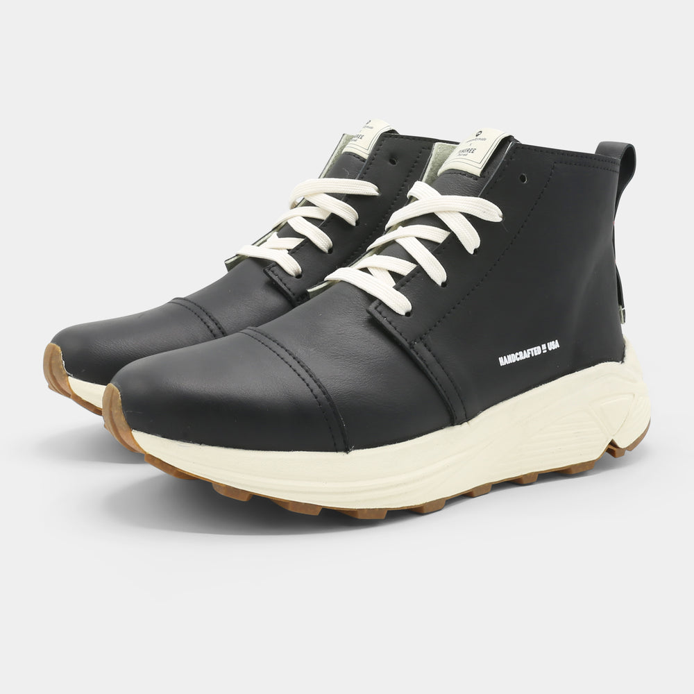 A black high-top urban utility chukka boot with white laces and a chunky white sole quarter view.