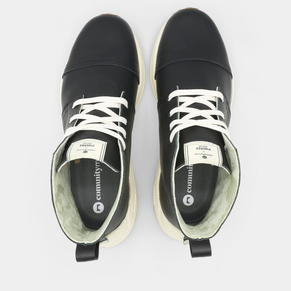 
                      
                        A black high-top urban utility chukka boot with white laces and a chunky white sole top view.
                      
                    
