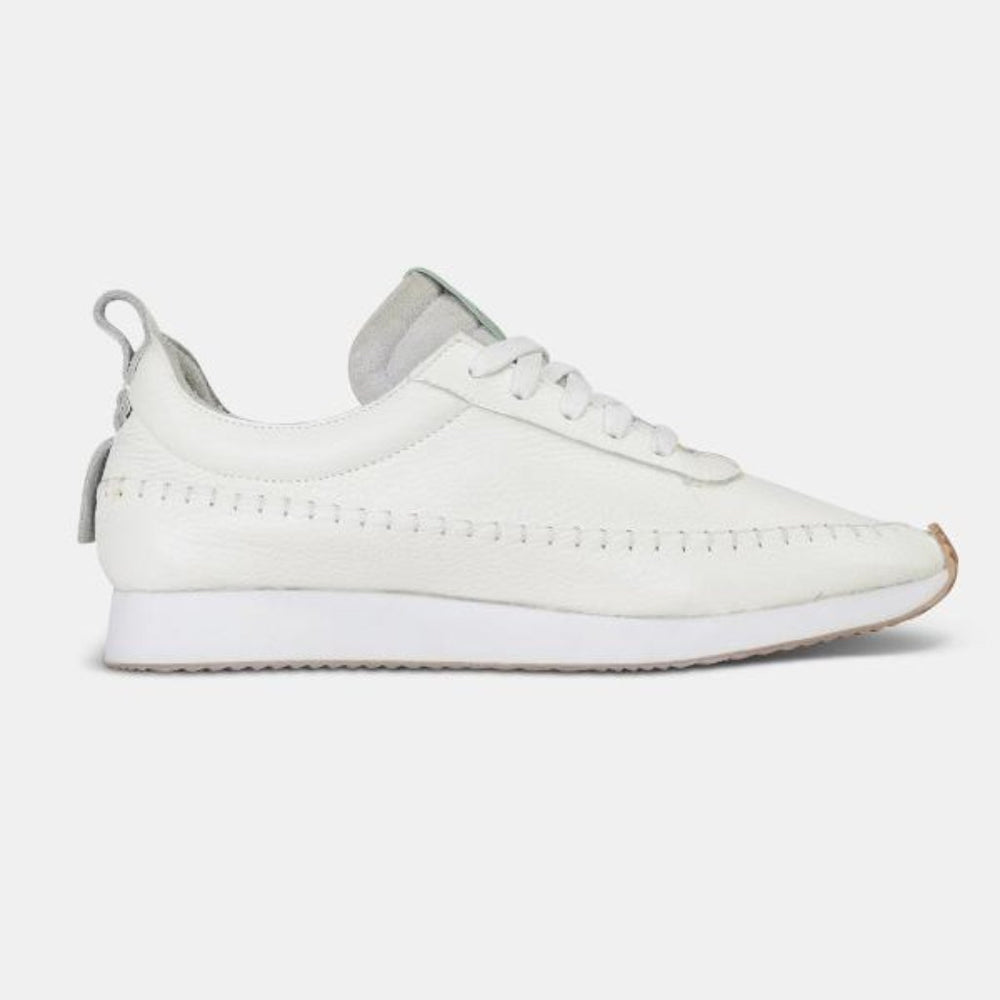 
                      
                        A inside profile shot of a single white Comunitymade lace-up shoe. The shoe is made of a white leather, flat white laces and has white accent stitching around the entire shoe plus a white heel pull tab. It has a flat white sole with a gum-rubber colored outsole.
                      
                    