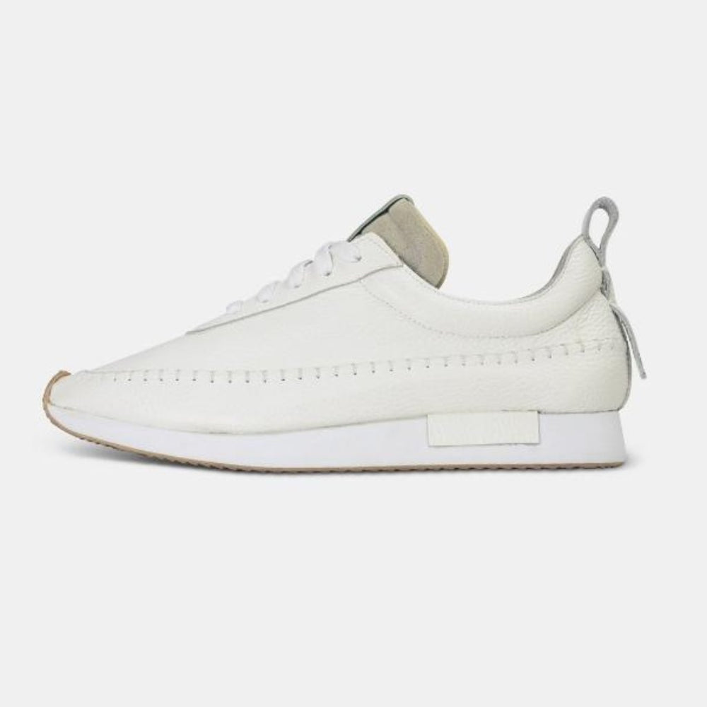 
                      
                        A side profile shot of a single white Comunitymade lace-up shoe. The shoe is made of a white leather, flat white laces and has white accent stitching around the entire shoe plus a white heel pull tab. It has a flat white sole with a gum-rubber colored outsole.
                      
                    