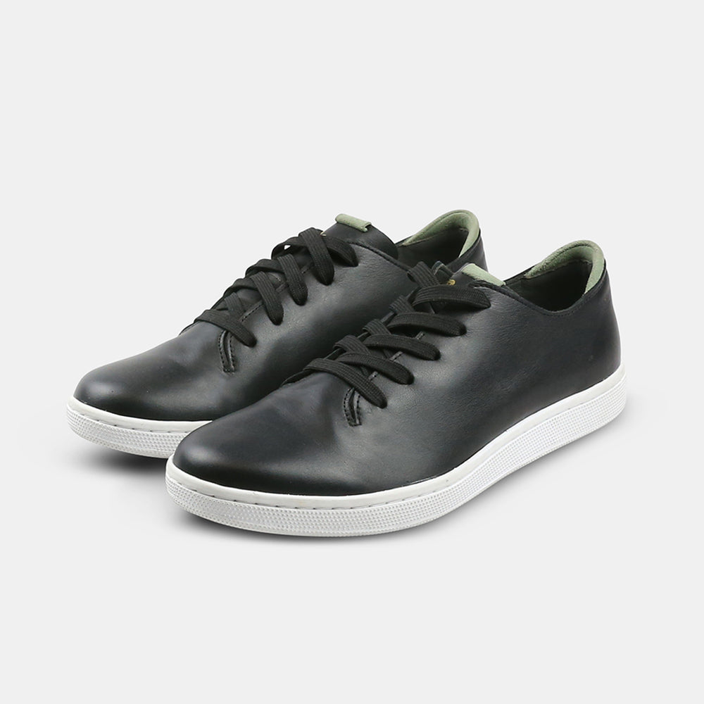 A quarter angle shot of pair of black leather sneakers with a lace-up closure featuring flat black shoelaces, a white rubber cupsole and a green accent on the heel.