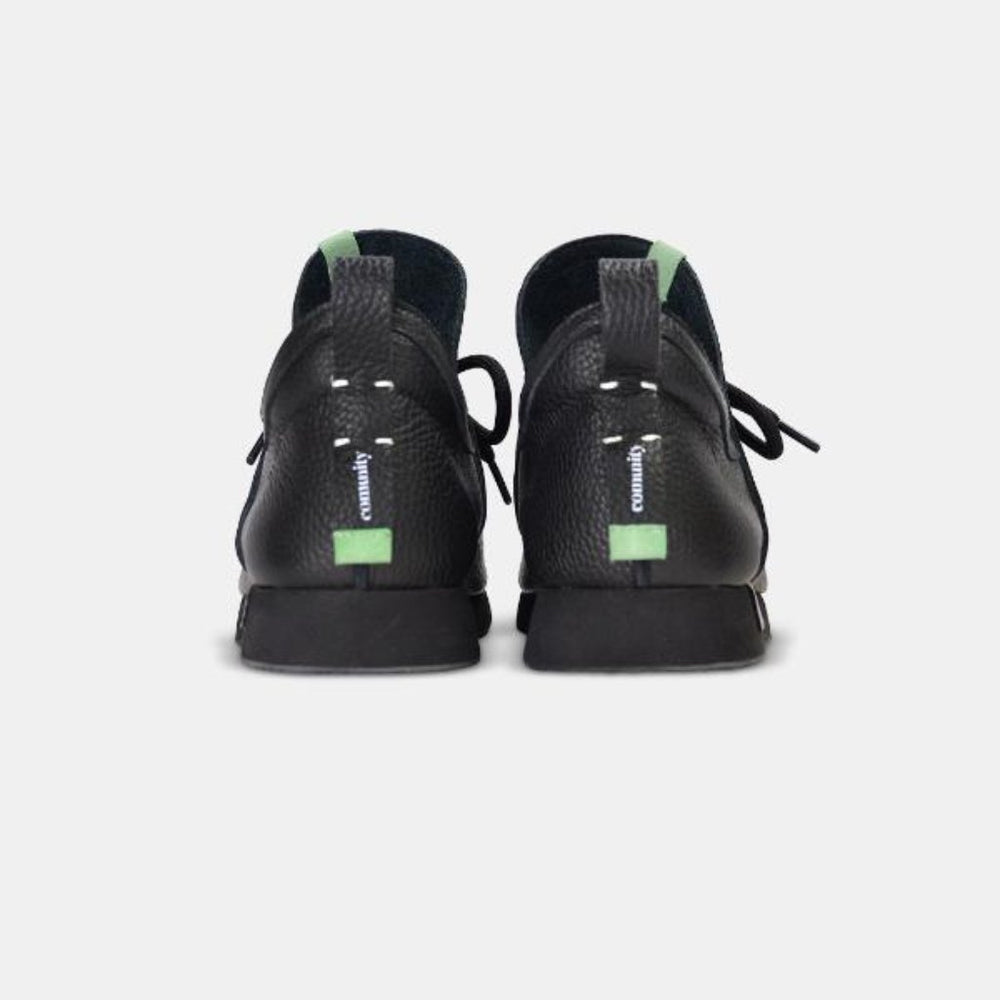 
                      
                        A rear view of a pair of casual black leather mid-cut slip-on shoe with a black heel loop pull tab with light green accents.  Showcases a black midsole with a black rubber outsole.
                      
                    