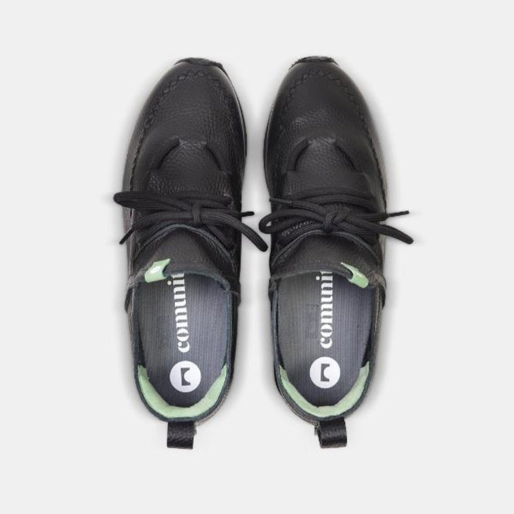 
                      
                        A top down view of a pair of casual black leather mid-cut slip-on shoe with unique stitch detailing on the toe and green branding accents.  Round black laces with heel loop pull tab. Insoles are dark grey with a round logo and COMUNITY printing in white.
                      
                    