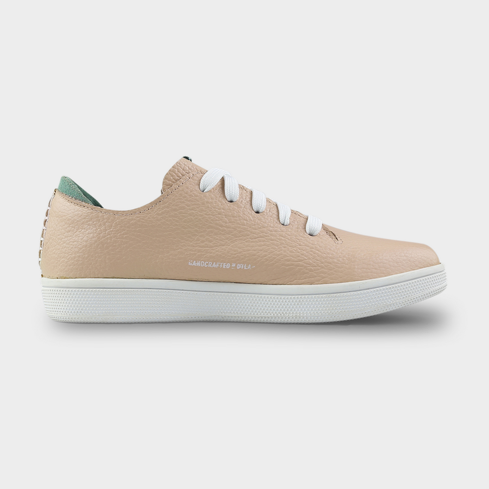
                      
                        A medial profile shot of single nude beige leather sneaker with a lace-up closure, featuring flat white shoelaces, white accent stitching on the heel, white "Handcrafted in LA" printing on the instep and a white rubber cupsole.
                      
                    