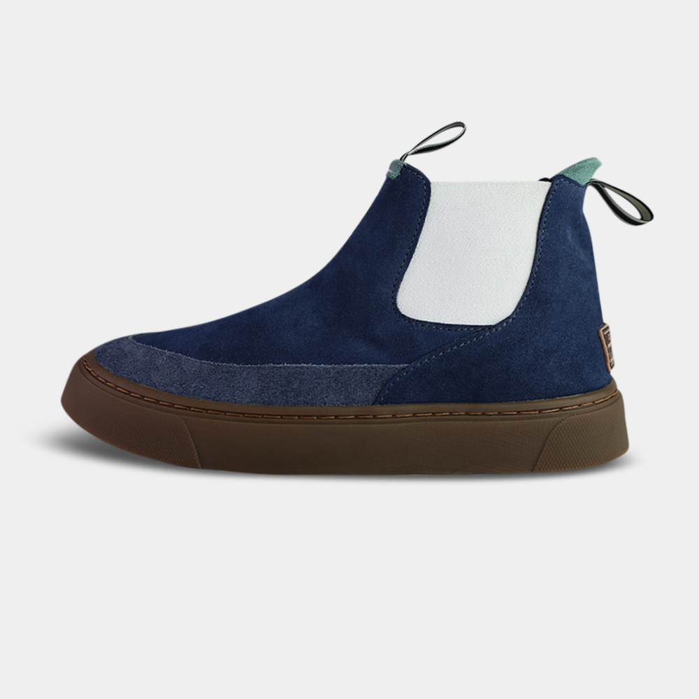 A navy blue and white mid-top women's sneaker with a pull-on design, featuring a rubber cupsole and a suede upper.