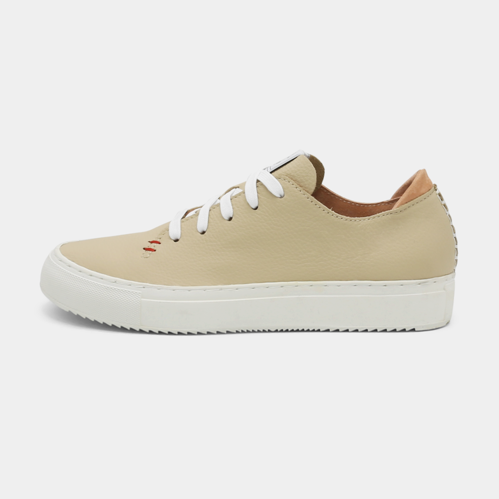 
                      
                        A cream colored low-top sneaker with a white sole and laces, lateral view.
                      
                    