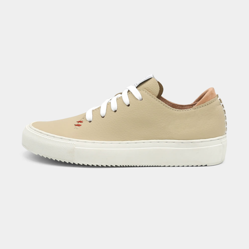 
                      
                        A cream colored low-top sneaker with a white sole and laces, lateral view.
                      
                    