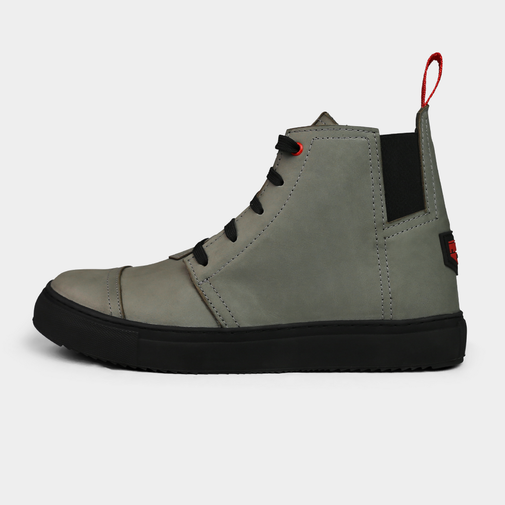 A stone grey, high-top sneaker with a solid black rubber outsole, featuring laces and a pull tab on the heel.