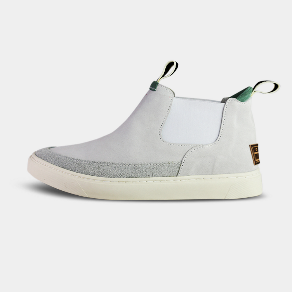 
                      
                        Side shot. A pair of white suede boots with white soles. The boots feature a mint green elasticated panel and a striped brown and black pull tab at the back of the ankle. The toe area is a different texture of suede with a visible seam.
                      
                    