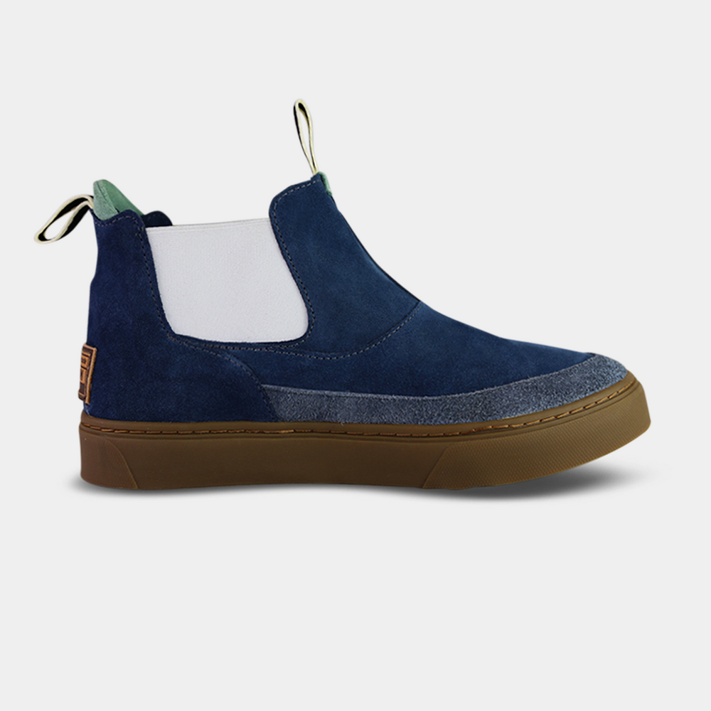 
                      
                        A pair of dark blue suede ankle boots with a brown rubber sole. The boots feature a light brown leather logo tag with "DEVIUM" written on the back of each heel, a mint green elasticated panel, and a black and white striped pull tab at the back of the ankle.
                      
                    