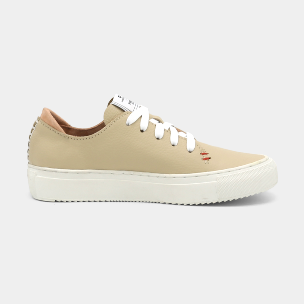 
                      
                        A cream colored low-top sneaker with a white sole and laces, lateral view.
                      
                    