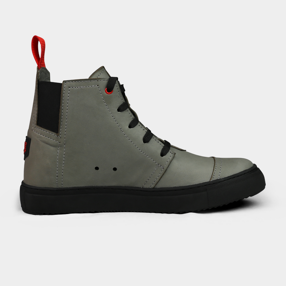 
                      
                        A product shot of the side of a pair of grey high-top shoes. The shoes are made of grey leather, with a black sole and a red loop on the back of the ankle. A red square with "PINGREE Detroit" written on it is visible on the heel of each shoe. The background is a solid light gray.
                      
                    