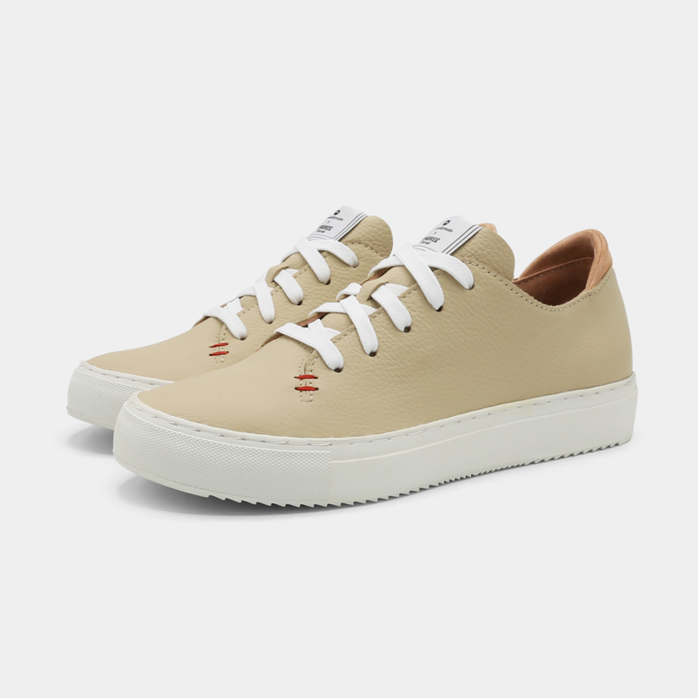 
                      
                        A cream colored low-top sneaker with a white sole and laces, quarter view.
                      
                    