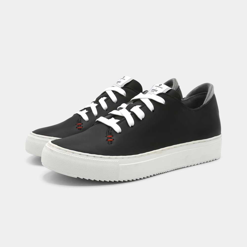 
                      
                        A black colored low-top sneaker with a white sole and laces, quarter view.
                      
                    