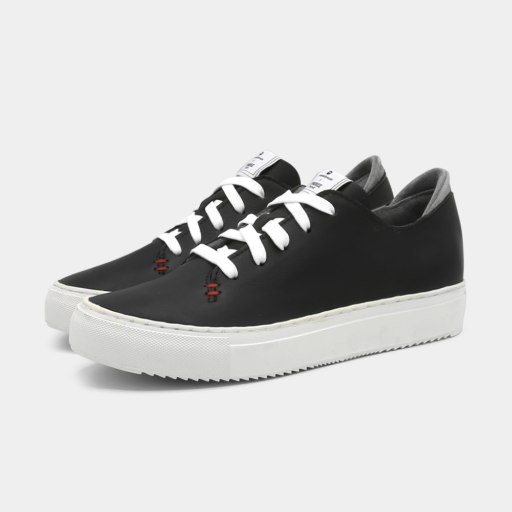 
                      
                        A black colored low-top sneaker with a white sole and laces, quarter view.
                      
                    