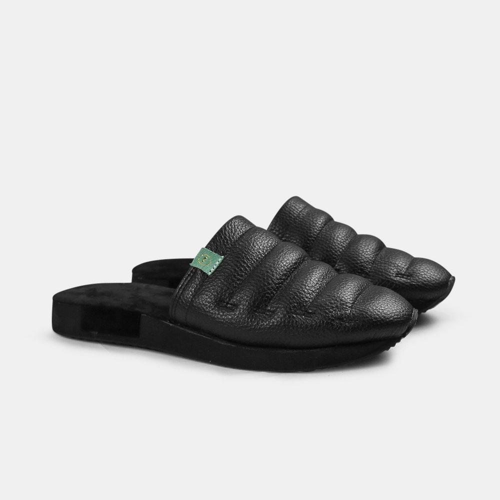 A men's Mateo slipper in black with a black rubber outsole, featuring a quilted design and a metallic accent quarter view