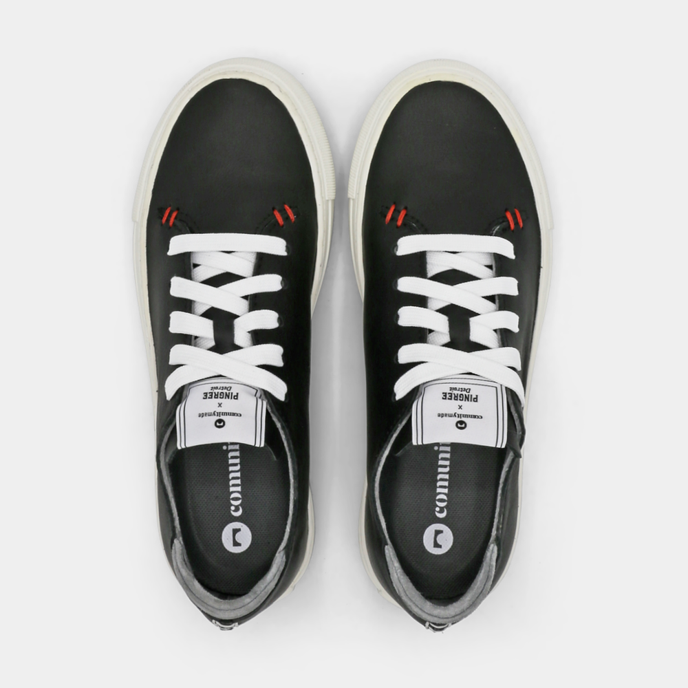 
                      
                        A black colored low-top sneaker with a white sole and laces, top view.
                      
                    