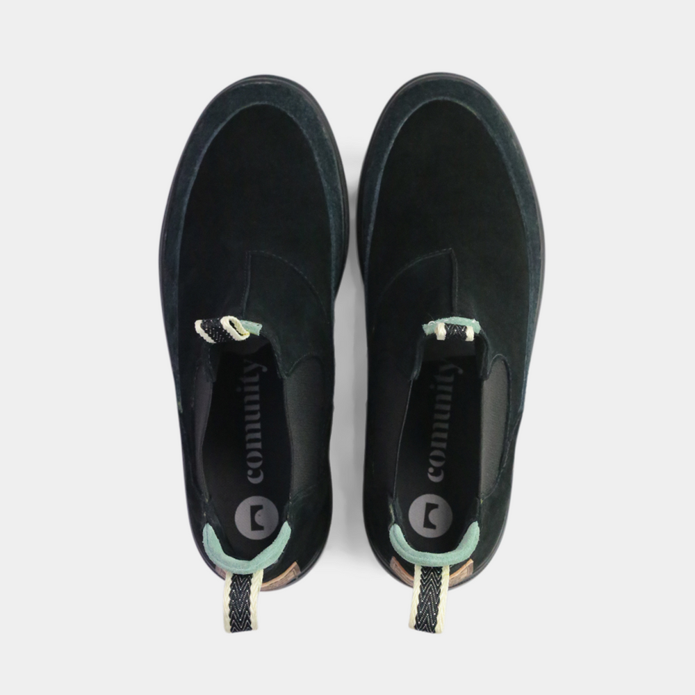 
                      
                        
A pair of black suede Chelsea boots. The shoes have black elastic gussets on the side and a striped pull tab at the heel. The black insoles feature a white "comunity" logo with a circle and an arrow.
                      
                    