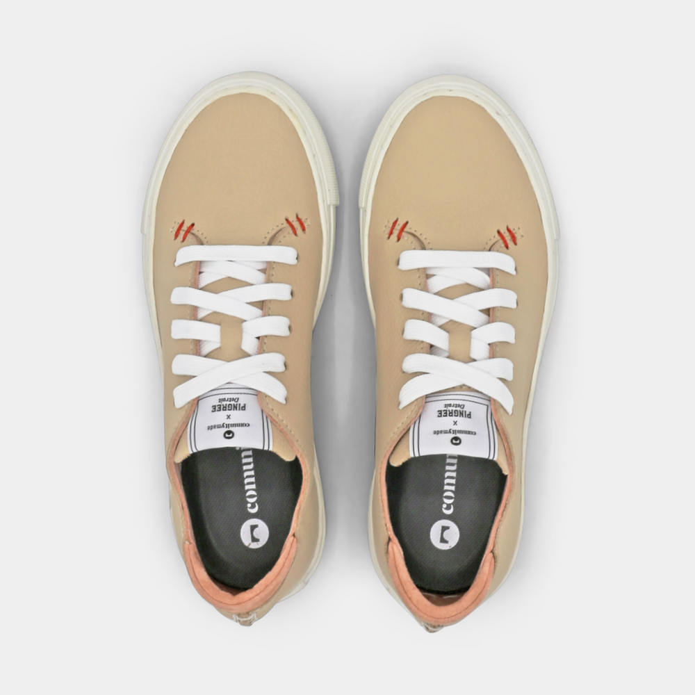 
                      
                        A cream colored low-top sneaker with a white sole and laces, top view.
                      
                    