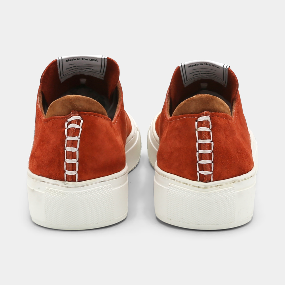 
                      
                        A rust colored low-top sneaker with a brown sole and laces, back view.
                      
                    