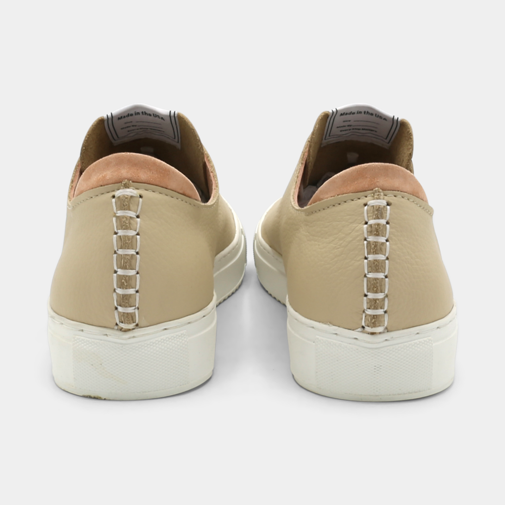
                      
                        A cream colored low-top sneaker with a white sole and laces, back view.

                      
                    