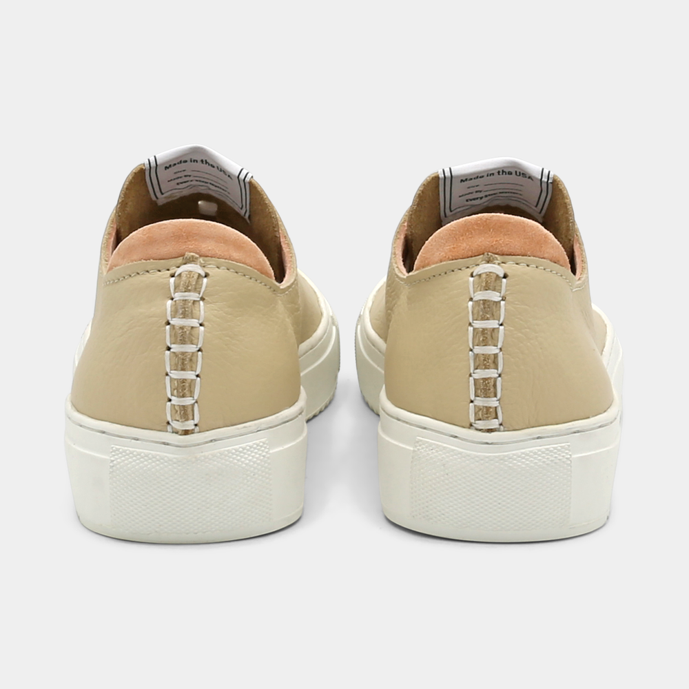 
                      
                        A cream colored low-top sneaker with a white sole and laces, back view.

                      
                    