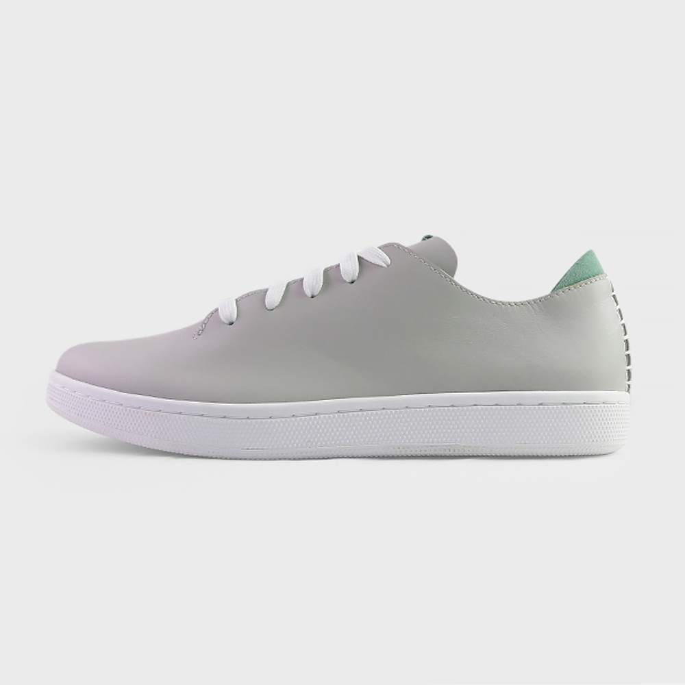 
                      
                        A profile shot of single light grey leather sneaker with a lace-up closure, featuring flat white shoelaces, a white rubber cupsole and a green accent on the heel.
                      
                    