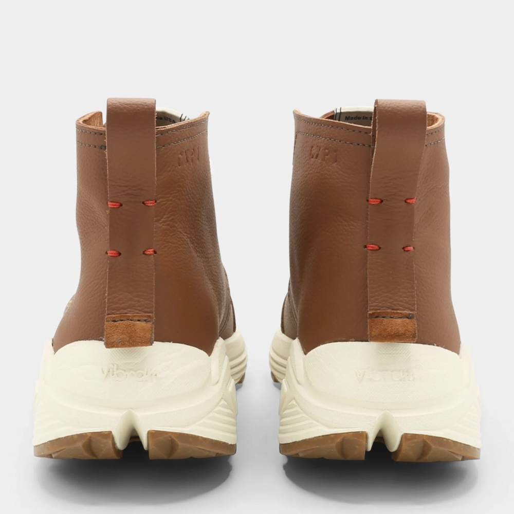 
                      
                        A brown high-top urban utility chukka boot with white laces and a chunky white sole back view.
                      
                    
